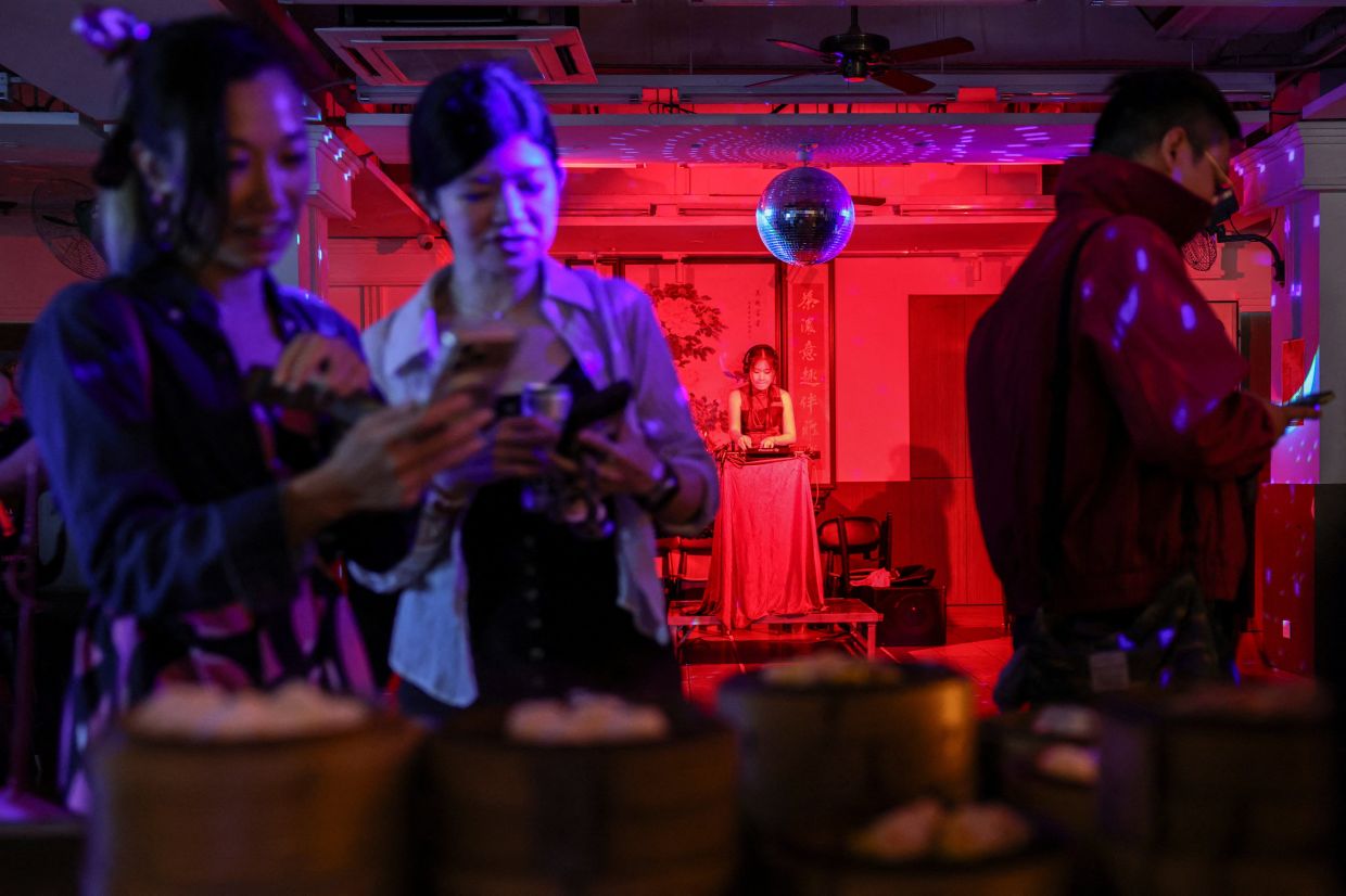 A DJ plays music as customers take photos of dim sums placed on traditional steamers at Lin Heung Lau teahouse.
