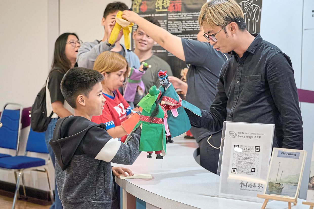 Audience members getting hands-on experience with ‘potehi’ puppets before the performance. — Handout