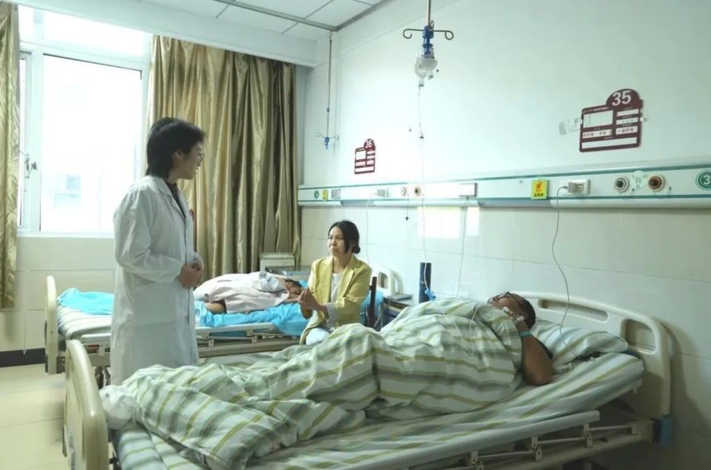 Ji Yaozhong lies in his hospital bed as a doctor tends to him alongside a visitor. - Photo: ifeng.com