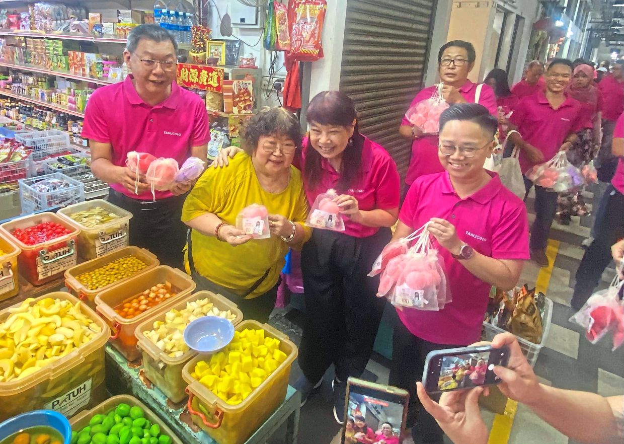 Lim (third from left) flanked by Teh (left) and Wong with Chowrasta Market visitors.