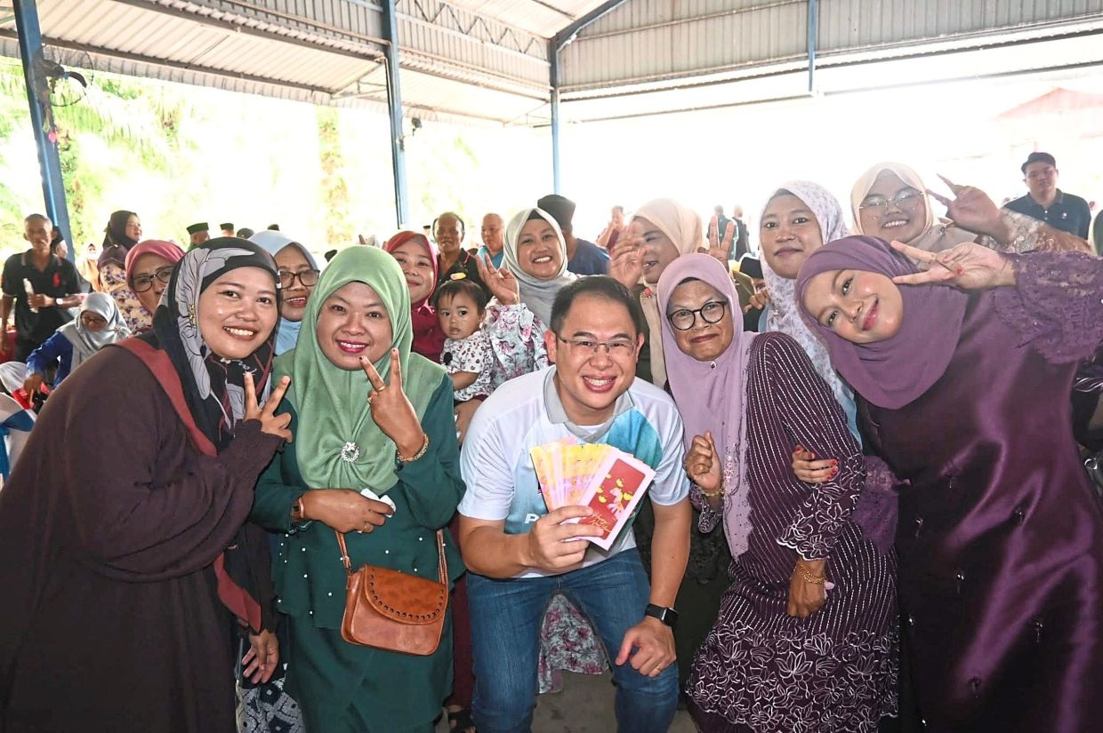 Ling handing out money packets to residents at a Raya Sekampung event at Kampung Sri Semangat, Yong Peng