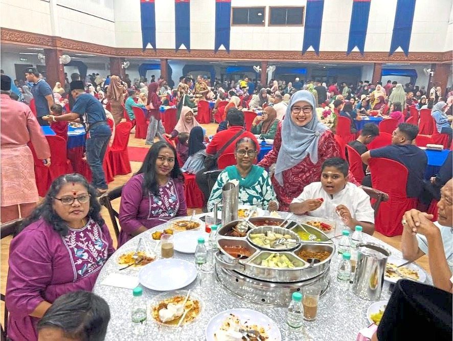 Neesa (seated second from left) and her family taking a photo with Hasrunizah at the open house in Pontian.