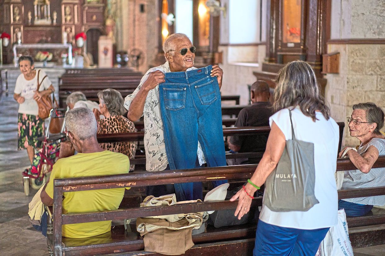 Carlos Lugo, 82, showing off a pair of jeans he received from charity before entering the dining hall adjacent to the Church of the Holy Spirit for a free meal. — AP