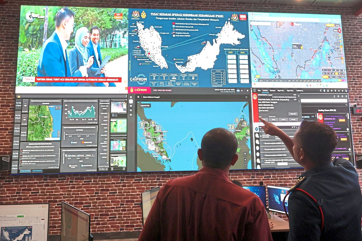 Modern solutions: Nor Hisham (right) explaining the different dashboards and screens used for the C4iFDRM at the Fire and Rescue Department headquarters in Putrajaya. — THOMAS YONG/The Star
