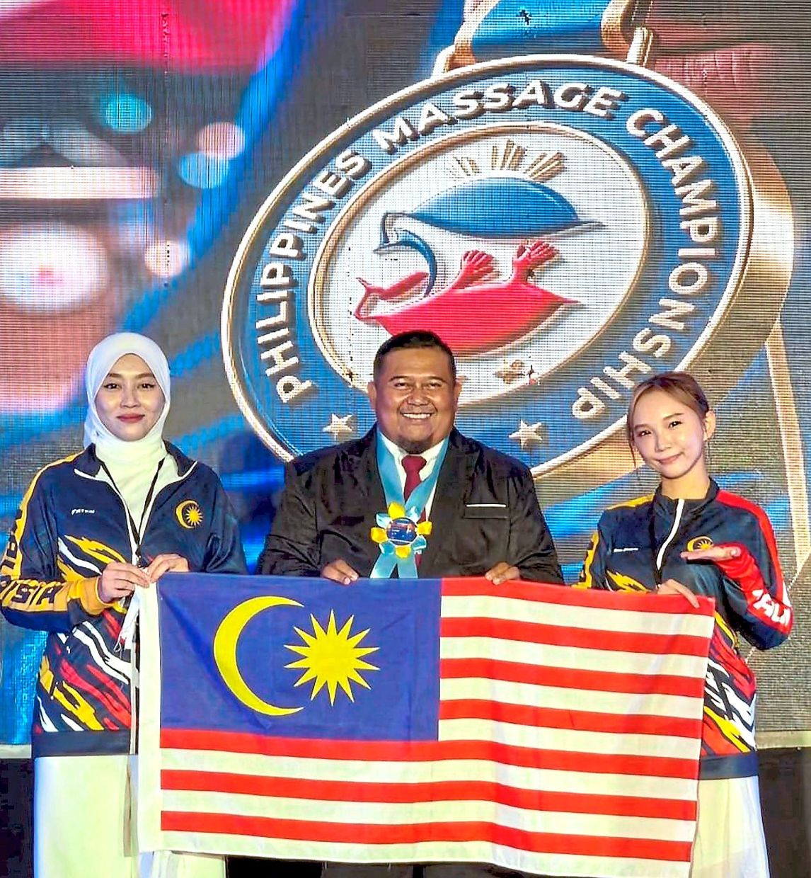 Healing touch: (From left) Faten Syahira, Hadafi Fitri and Lim proudly holding the Jalur Gemilang after clinching excellent results at the World Massage Championship in the Philippines.