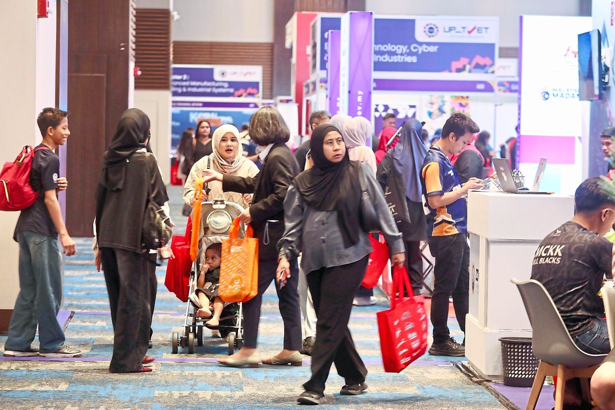 Greater insight: (From left) Visitors checking out various booths at the Star Education Fair, and ADTEC JTM Shah Alam staff member Muhammad Firdaus Zakaria.