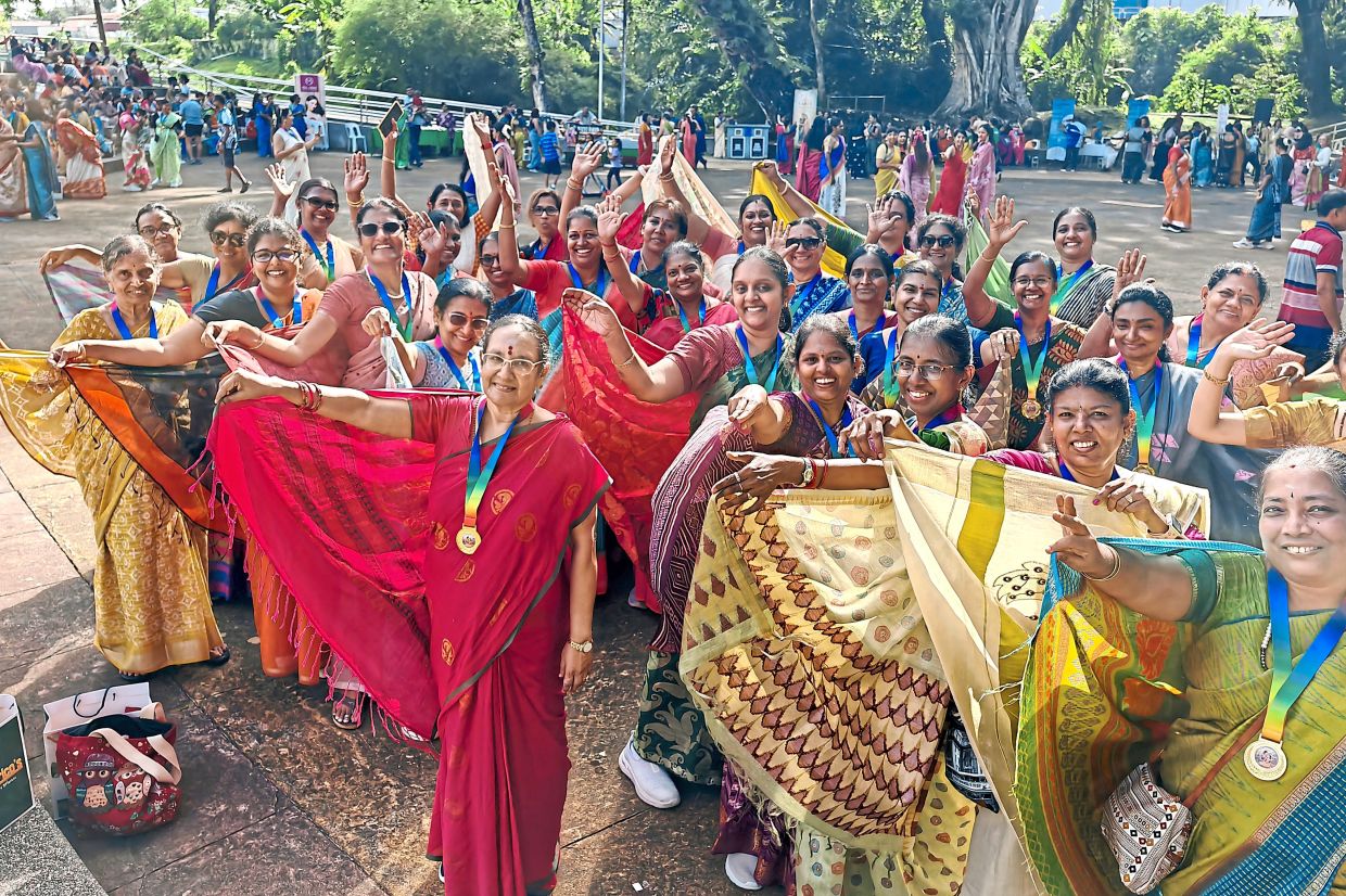 Participants clad in vibrant sarees, with their medals at the Penang City Park after the 2km walkathon.