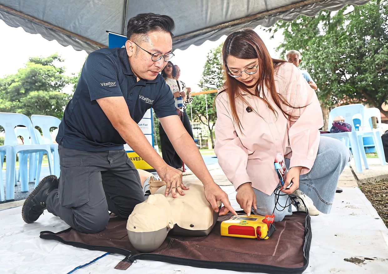 Jamaliah (right) being instructed on use of an AED alongside techniques of CPR during the programme in Petaling Jaya.