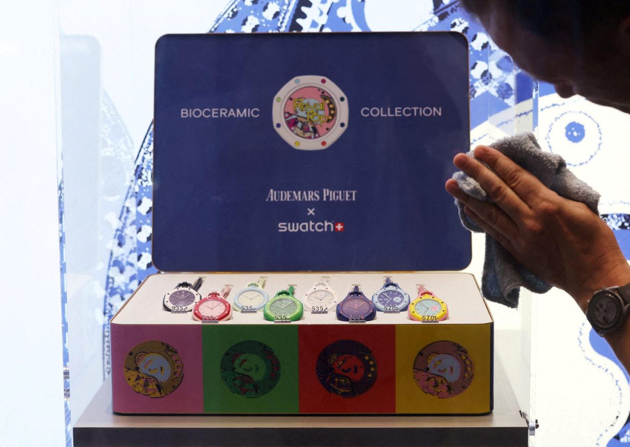 A member of staff cleans a display box of Audemars Piguet and Swatch's Royal Pop watches on launch day at Orchard ION mall in Singapore. -- Photo: REUTERS/Edgar Su