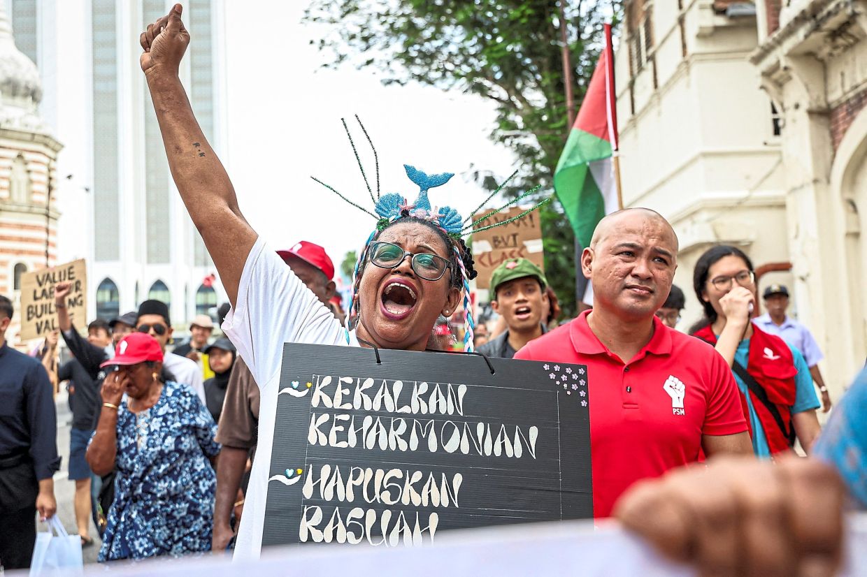 A protester raises fist while holding a placard that reads ‘Maintain harmony, eliminate corruption’ during the rally marking workers’ rights and labour solidarity in Kuala Lumpur. — Reuters