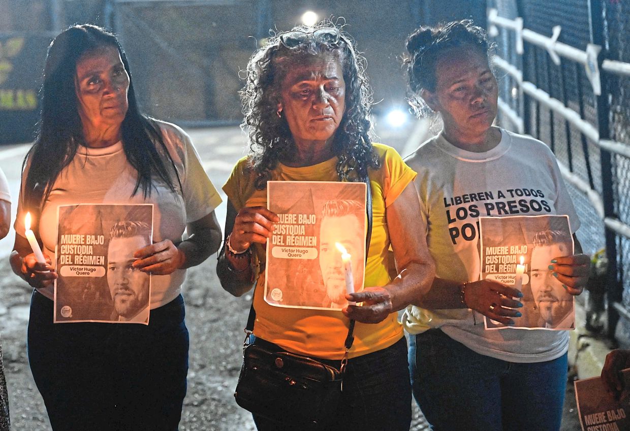 Women holding signs bearing the image of late Venezuelan political prisoner Victor Hugo Quero Navas during a Mothers Day demonstration outside El Rodeo I prison in Guatire, Venezuela. — AFP