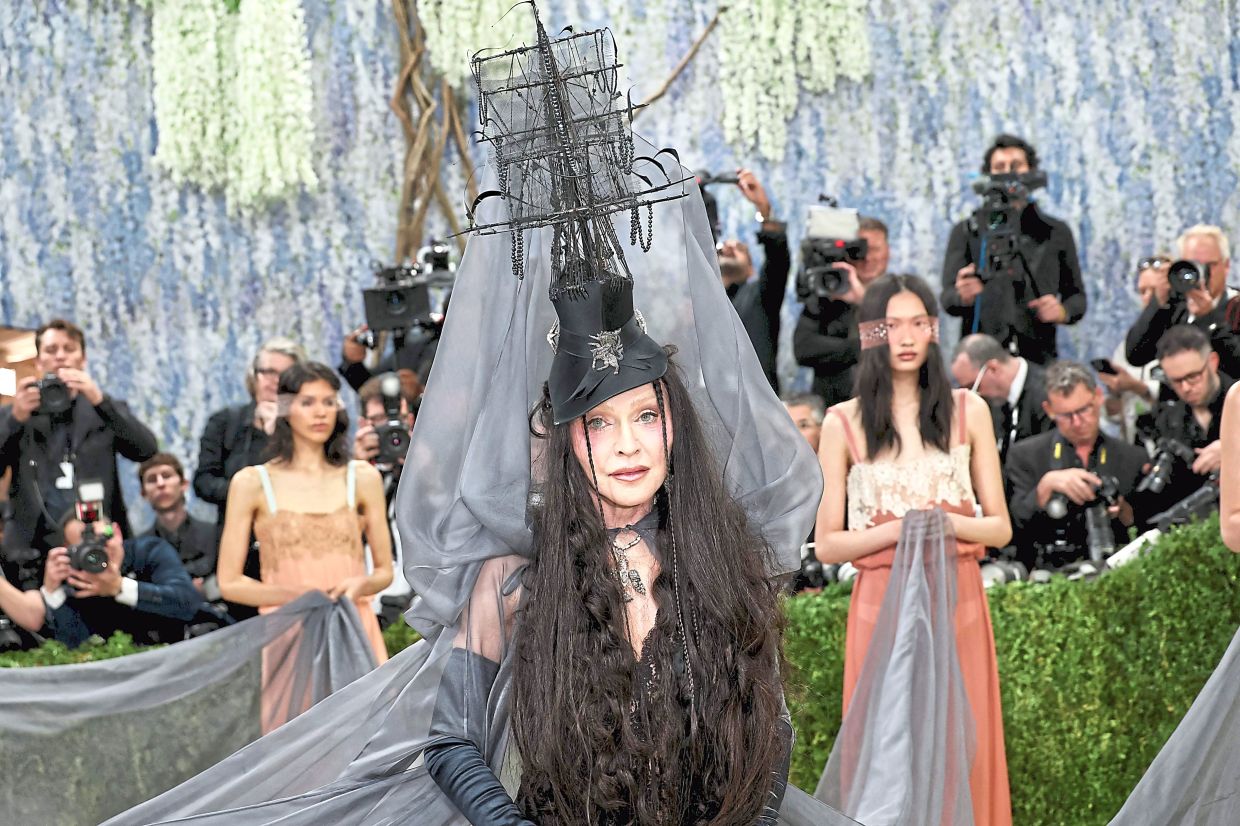 Queen of pop Madonna wore a dramatic ruffled black gown by Anthony Vaccarello for Yves Saint Laurent, evoking the surrealist world of Leonora Carrington with a golden horn and ship-inspired headpiece draped in a sheer veil. — Getty Images via AFP