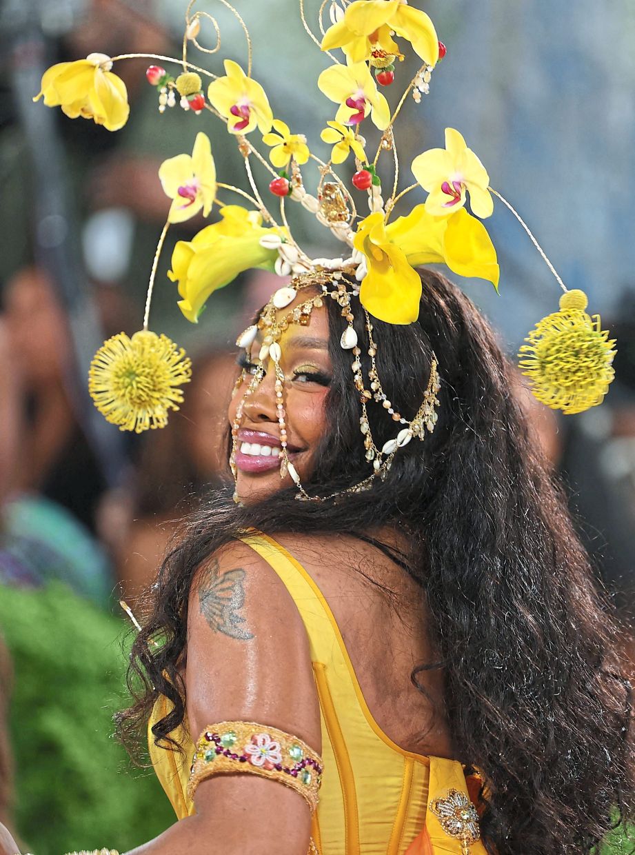 US singer Sza dazzled in a romantic sunyellow gown inspired by butterfly wings and 18th-century silhouettes, adorned with beads, sequins and cowrie shells, designed by Emily Adams Bode Aujla for Bode. — AFP