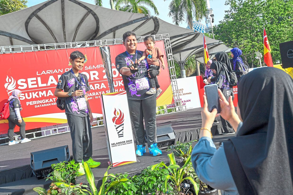 A family taking the opportunity to pose with the sukma torch.Right: The torch, pictured here carried by Shah Alam mayor Datuk Zabidah Safar with Mohd Najwan to her left, will tour Selangor in the run-up to Sukma and Para Sukma 2026.