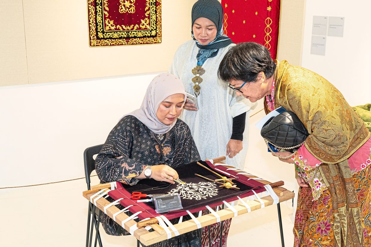 'Inspired by TEKAT' advisor and tekat practitioner Nor Faizatol Fazleha Mohd Rasdi (Kak Faz) demonstrates the traditional technique of tekat benang emas embroidery at the show's opening. — Handout
