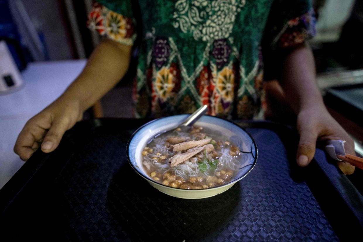 A woman carries a Rakhine traditional noodle dish called Mote Ti at a Rakhine restaurant in Yangon.