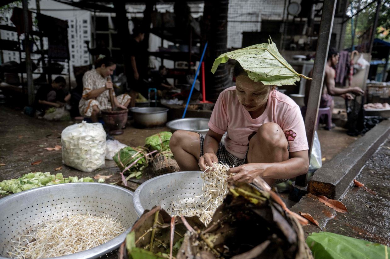 A woman prepares ingredients to cook at a Rakhine traditional food restaurant in Yangon on May 15, 2026. War has besieged diets in west Myanmar, but chefs smuggle out flavours of local cuisine: delicate noodles and briny broth from a region where conflict blights harvests of the land and sea. (Photo by Sai Aung MAIN / AFP) / TO GO WITH AFP STORY:Myanmar-food-culture, FOCUS