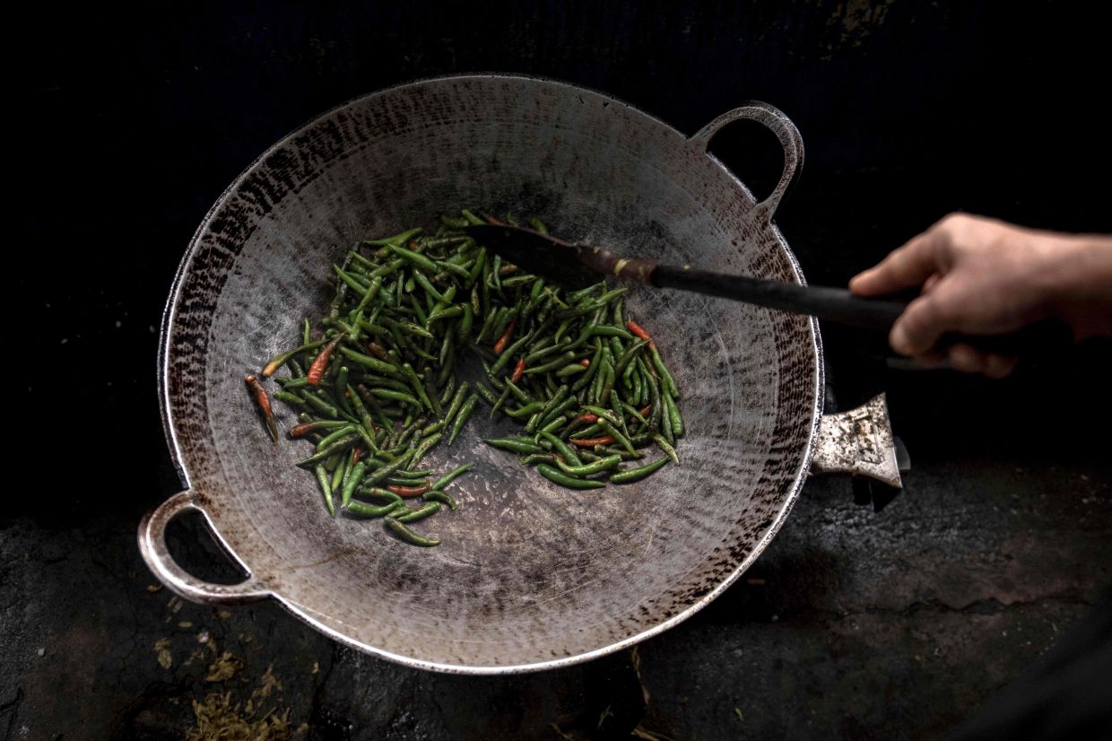 A vendor cooks a dish at a Rakhine traditional food restaurant in Yangon.
