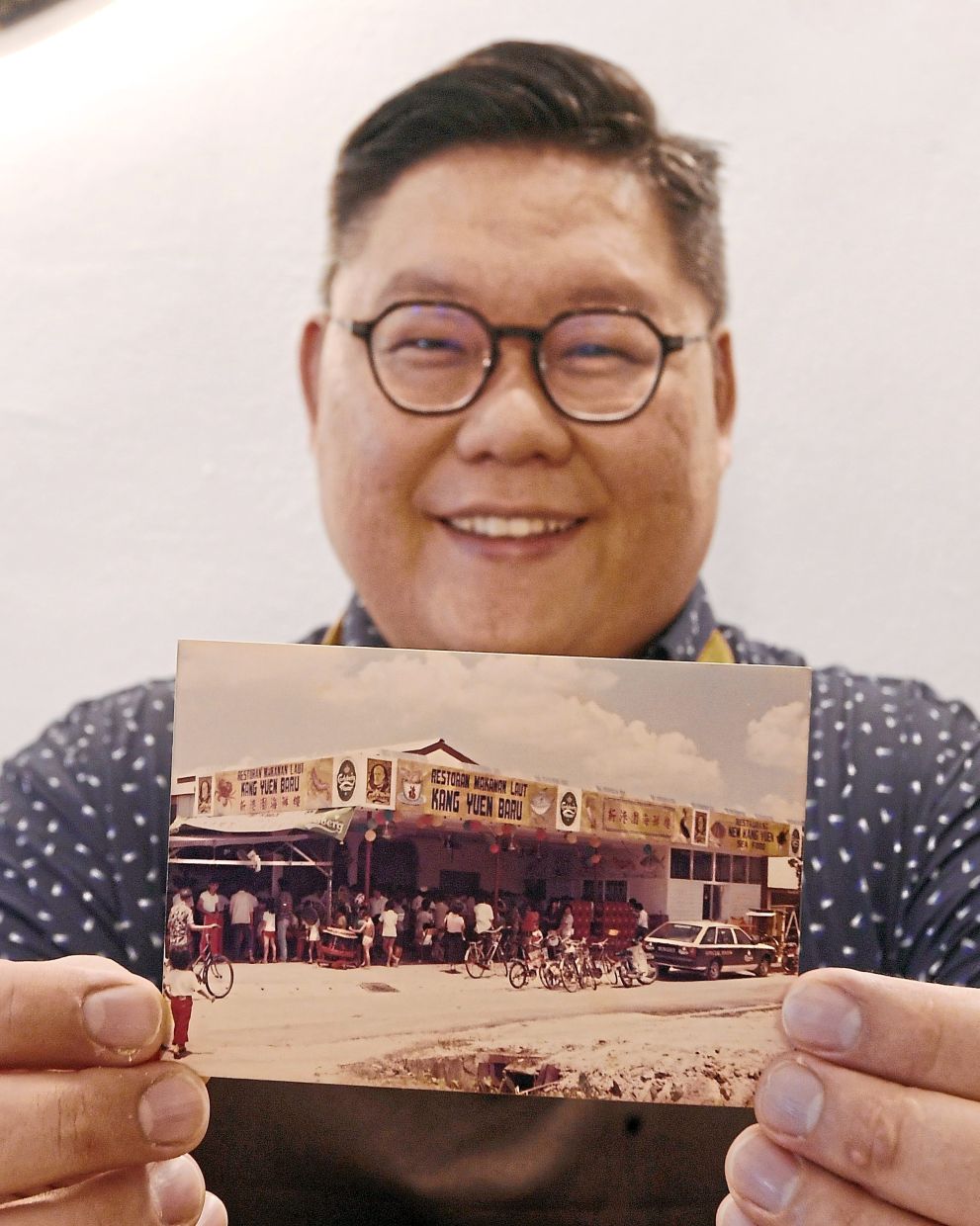 Ng holding a photo of his parents’ old restaurant in Klang.
