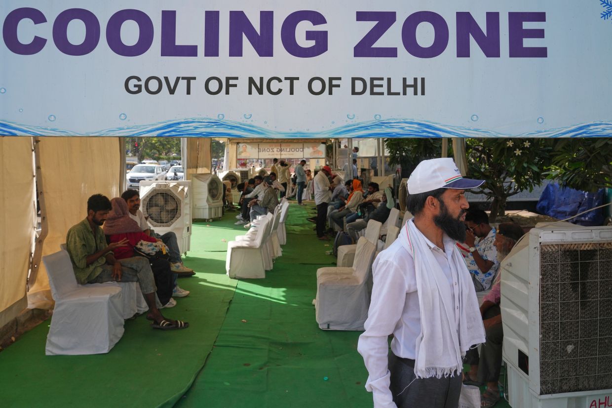 Commuters resting at a roadside cooling station set up by the government to provide relief for people from the intense summer heat in New Delhi. - AP