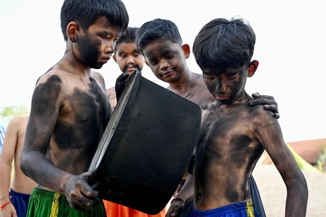 A group of boys used charcoal residue from a cooking pot to paint themselves black, drawing inspiration from local folklore. - Photo: AFP