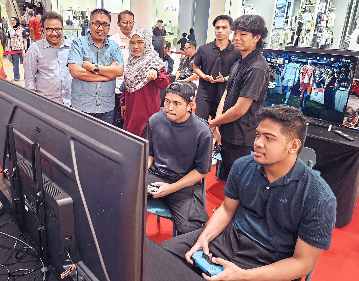 Safriah (wearing red) with Shahrin (left) and Mohd Firdaus (second from left) watching the gamers as they compete in the Shah Alam Esports Championship 2026.