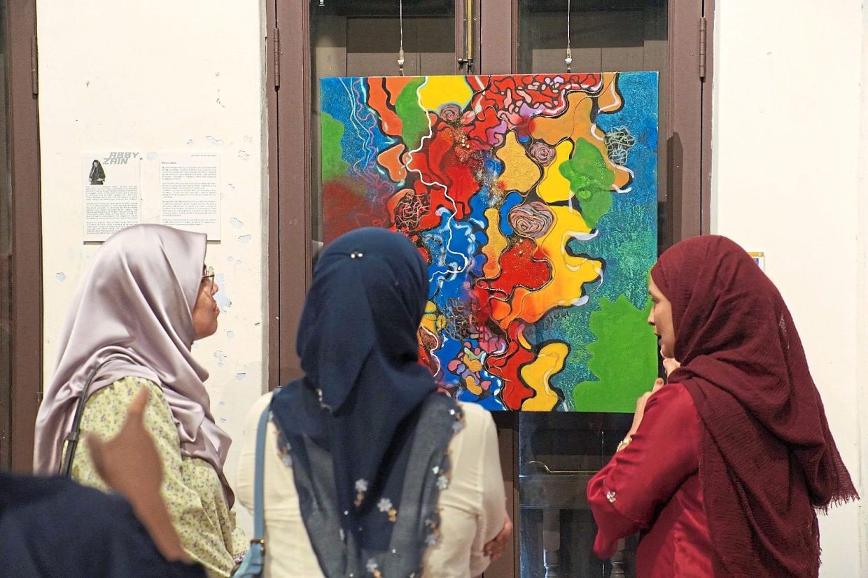 Arbaayah (right) explaining her painting to Jamilah (left) and Rabaai. — Handout