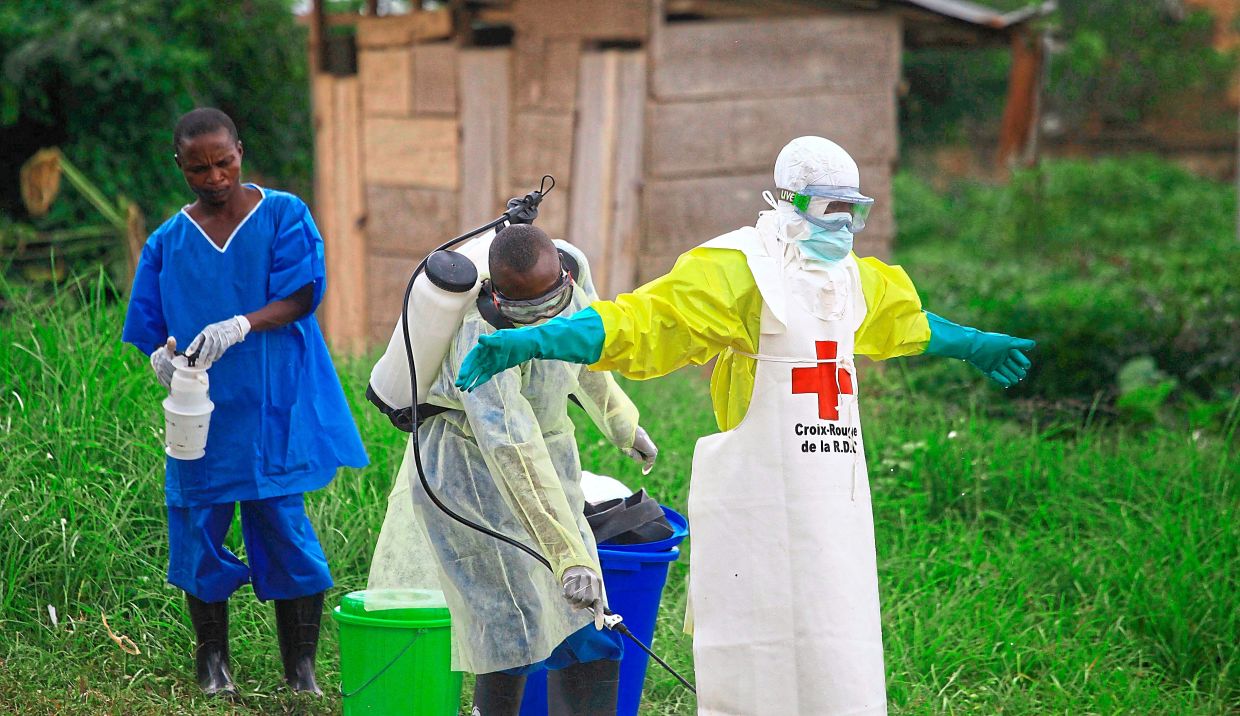 A health worker sprays disinfectant on his colleague after finishing a shift at an Ebola treatment centre in Beni, Congo.