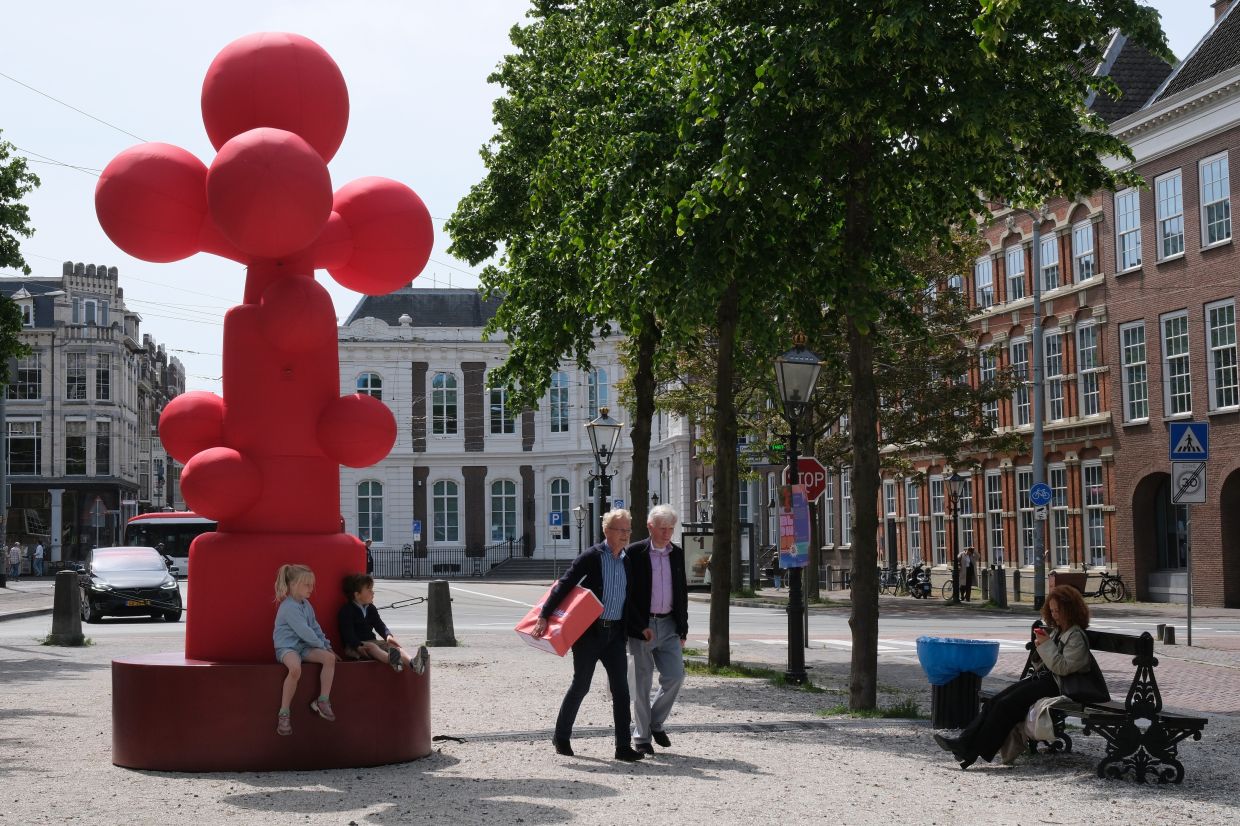 Two men walk past an art installation titled 'Growth' by Piet Warffemius as part of the BlowUp Jubilee Art walk in the Hague, Netherlands. Photo: AP 