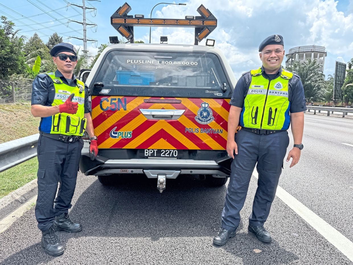 Shamierul (right) and Asyrof from PLUS auxiliary police came to this driver’s rescue on the highway near Bandar Baru Bangi, Kajang. — GRACE CHEN/The Star