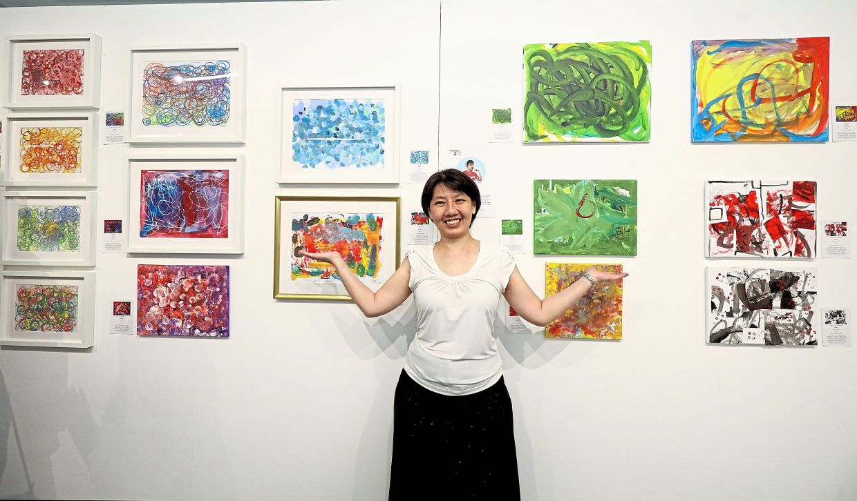 Lee with her son Cory’s artworks featured at the exhibition.