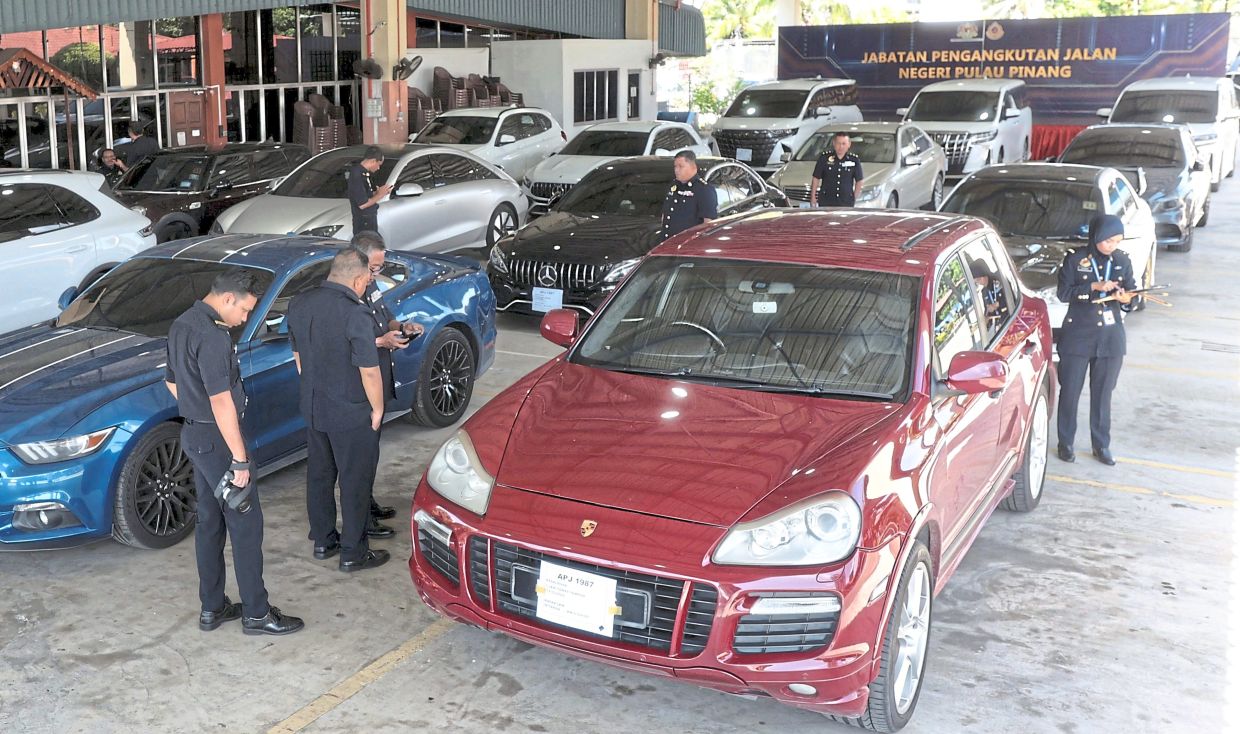 Off the roads: JPJ officers checking some of the seized luxury cars at JPJ headquarters in Seberang Jaya, Penang. — ZHAFARAN NASIB/The Star.