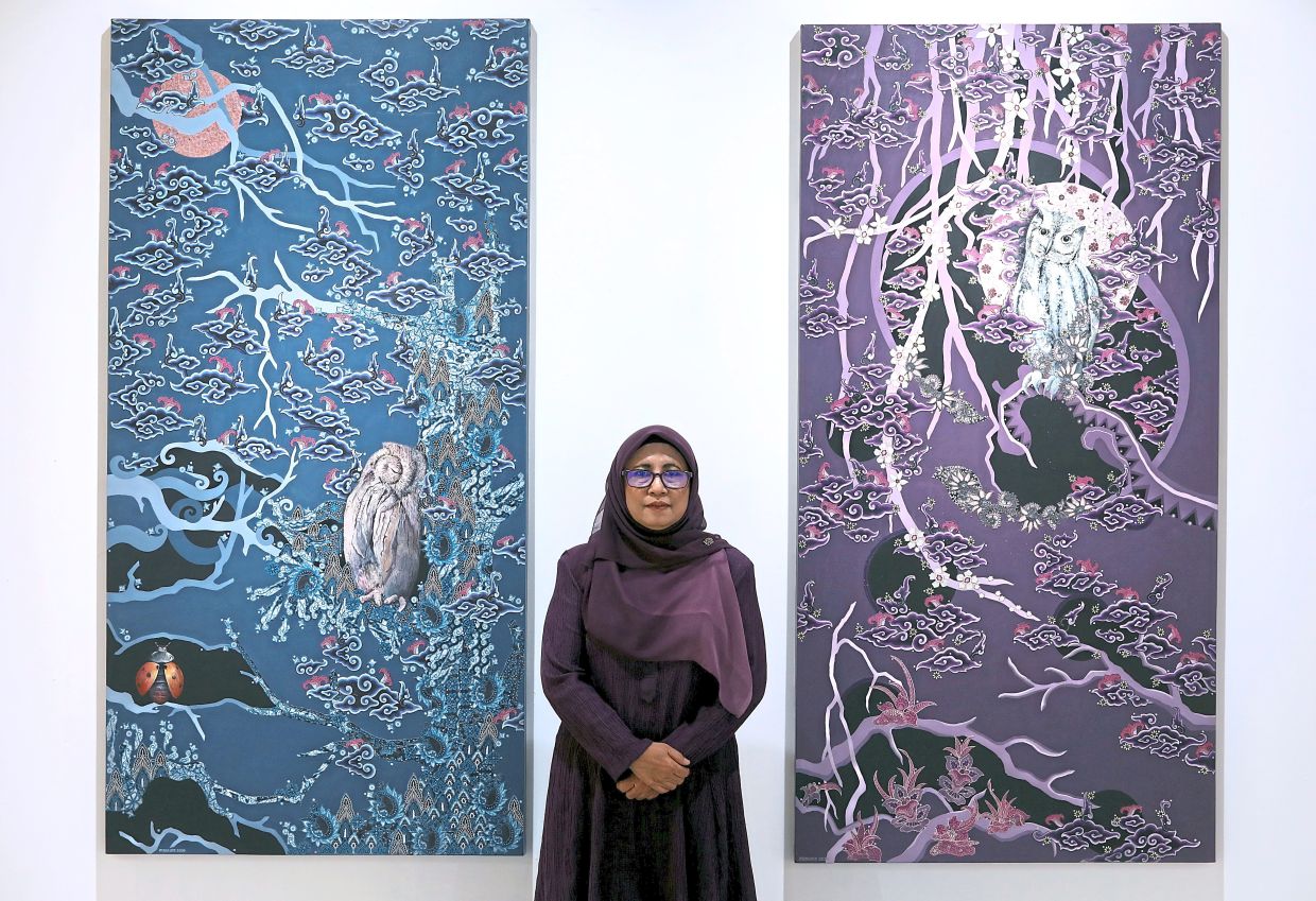 Mastura stands between her works 'Bicara Pungguk 6: Lagu Merindu Kasih' (left) and 'Bicara Pungguk 4: Pada Geta / Kota Rembulan'. Photo: The Star/Azlina Abdullah 