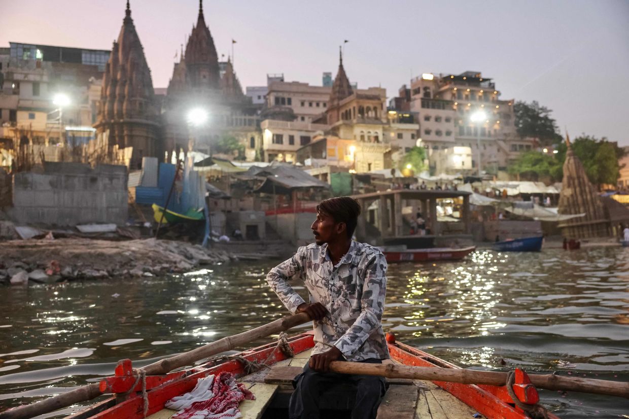 TOPSHOT: A man rows a boat across the river Ganges in India's sacred city of Varanasi, famed for its temples and Hindu festivals. -- Photo by Niharika KULKARNI / AFP