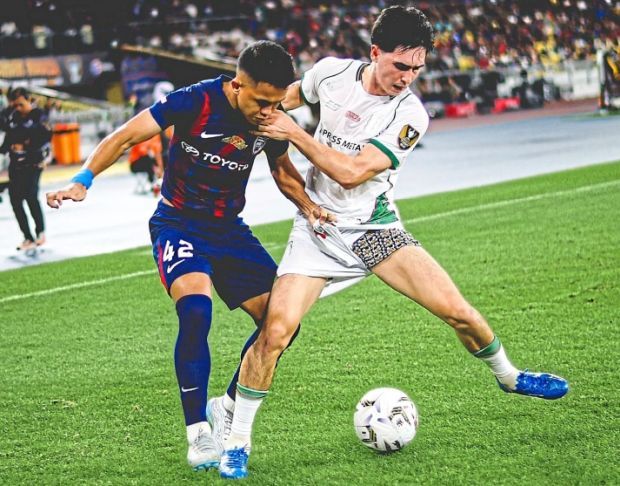 Back in action: JDT’s Arif Aiman Hanapi (left) fighting for the ball with a Kuching City player. — JDT