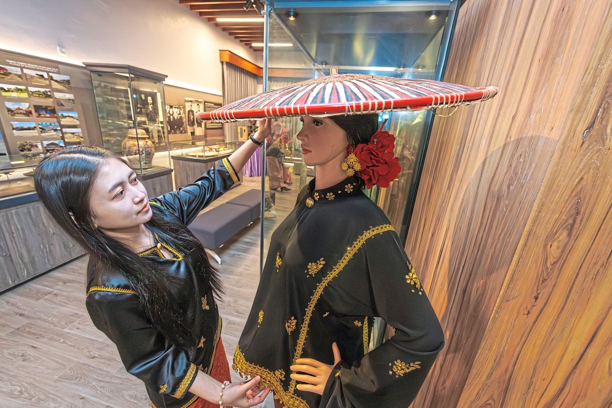 A gallery staff member adjusting the display of a traditional Melanau costume.