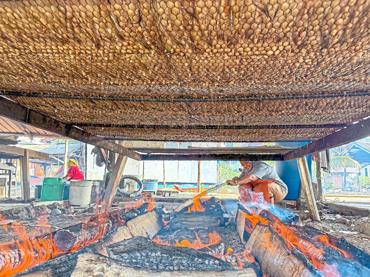 Villagers tending the fire to smoke the fish.