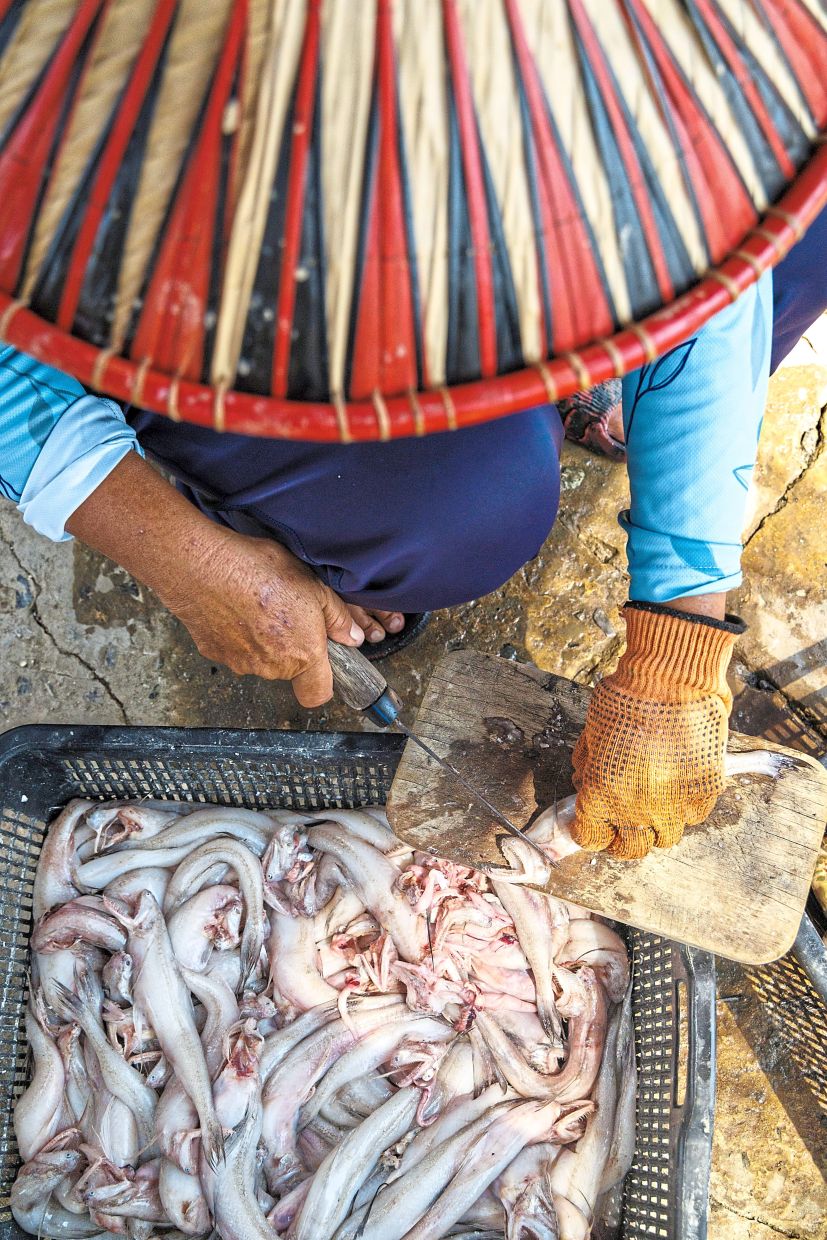 A villager cleaning the fish before it is smoked.