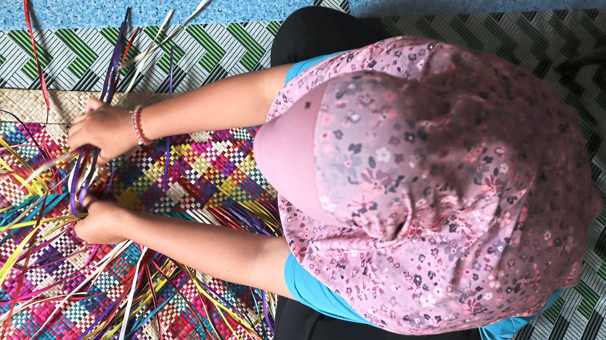 A resident weaving colourful handicrafts at her home on Pulau Libaran.