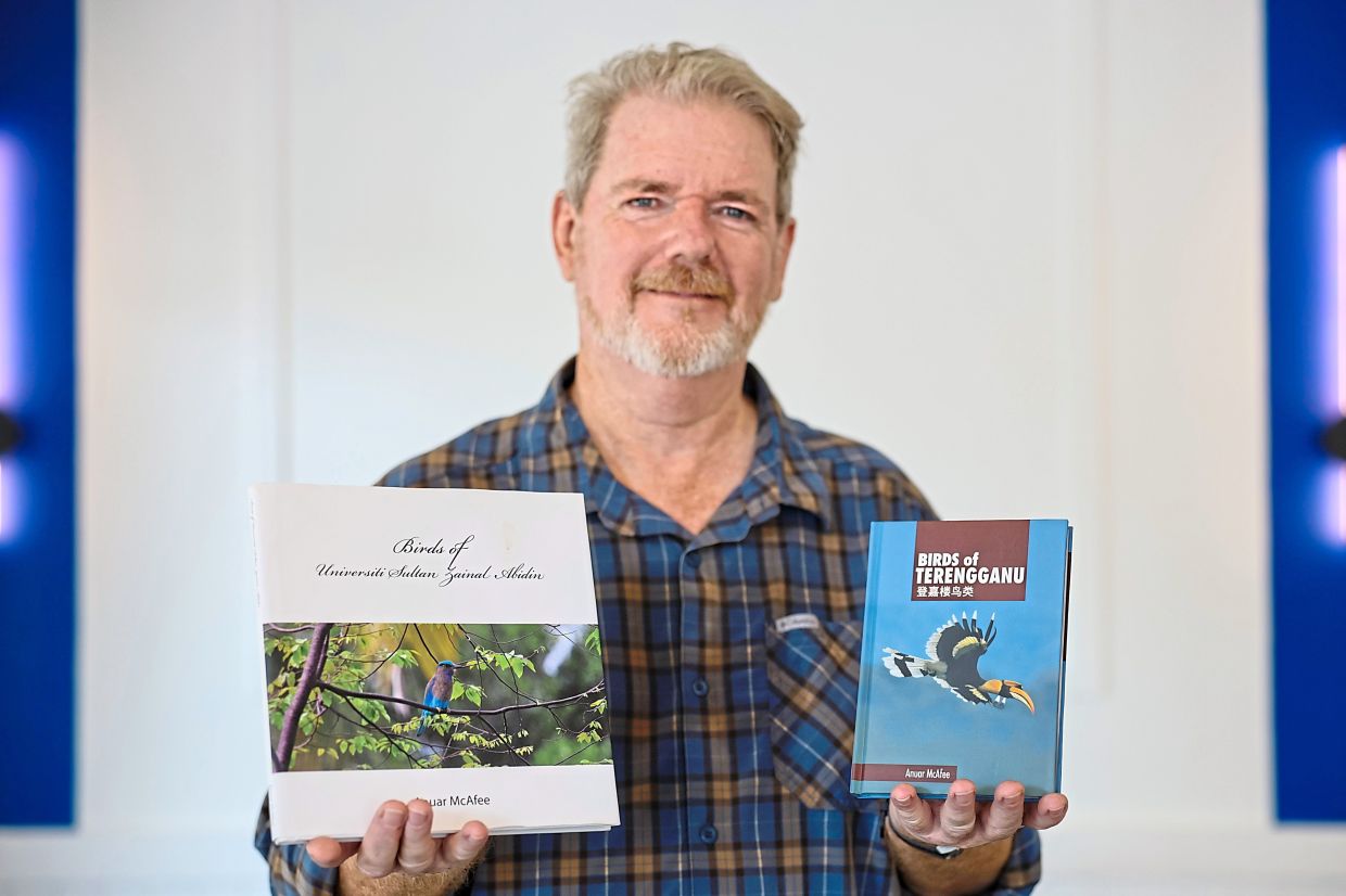 Cornelius showing the books he has published on bird species.