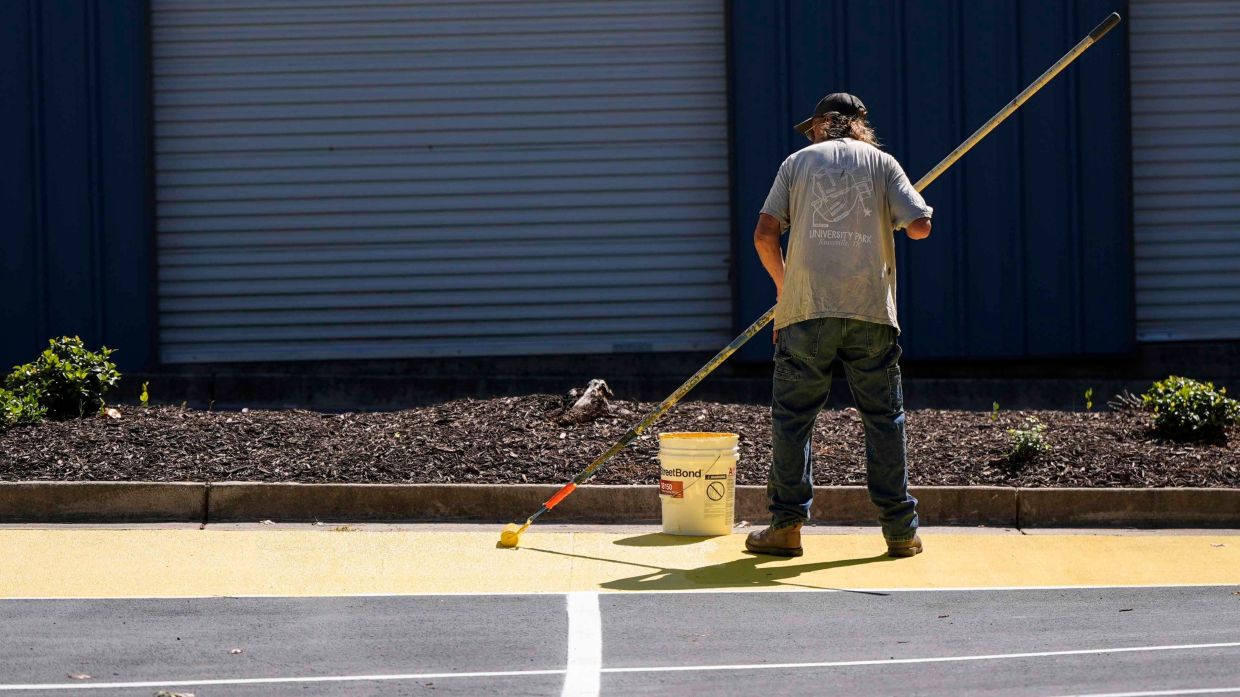 Ronnie Jefferies paints the parking lot at Science, Arts and Entrepreneurship School to help cool it by making it more reflective, Sept. 4, 2024, in Mableton, US. — Photo: AP/Mike Stewart