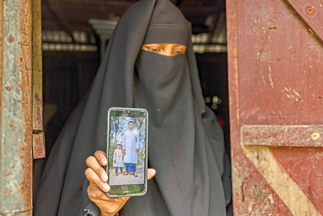 Family shattered: Sadia showing a photo of her late husband and their son on a mobile phone in Rasulpur village, Bangladesh. — AP