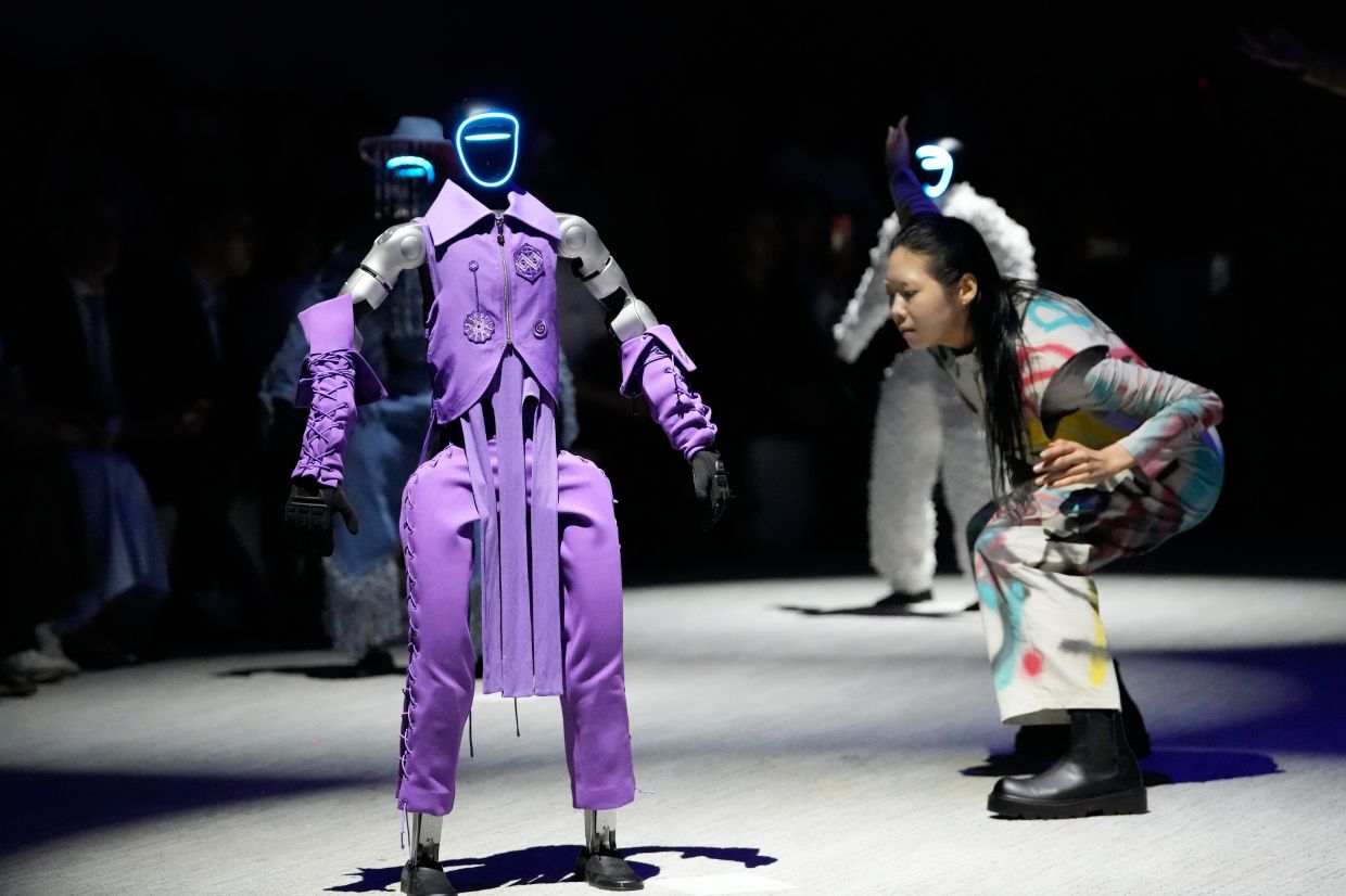 A humanoid robot and a model on the runway. - AP
