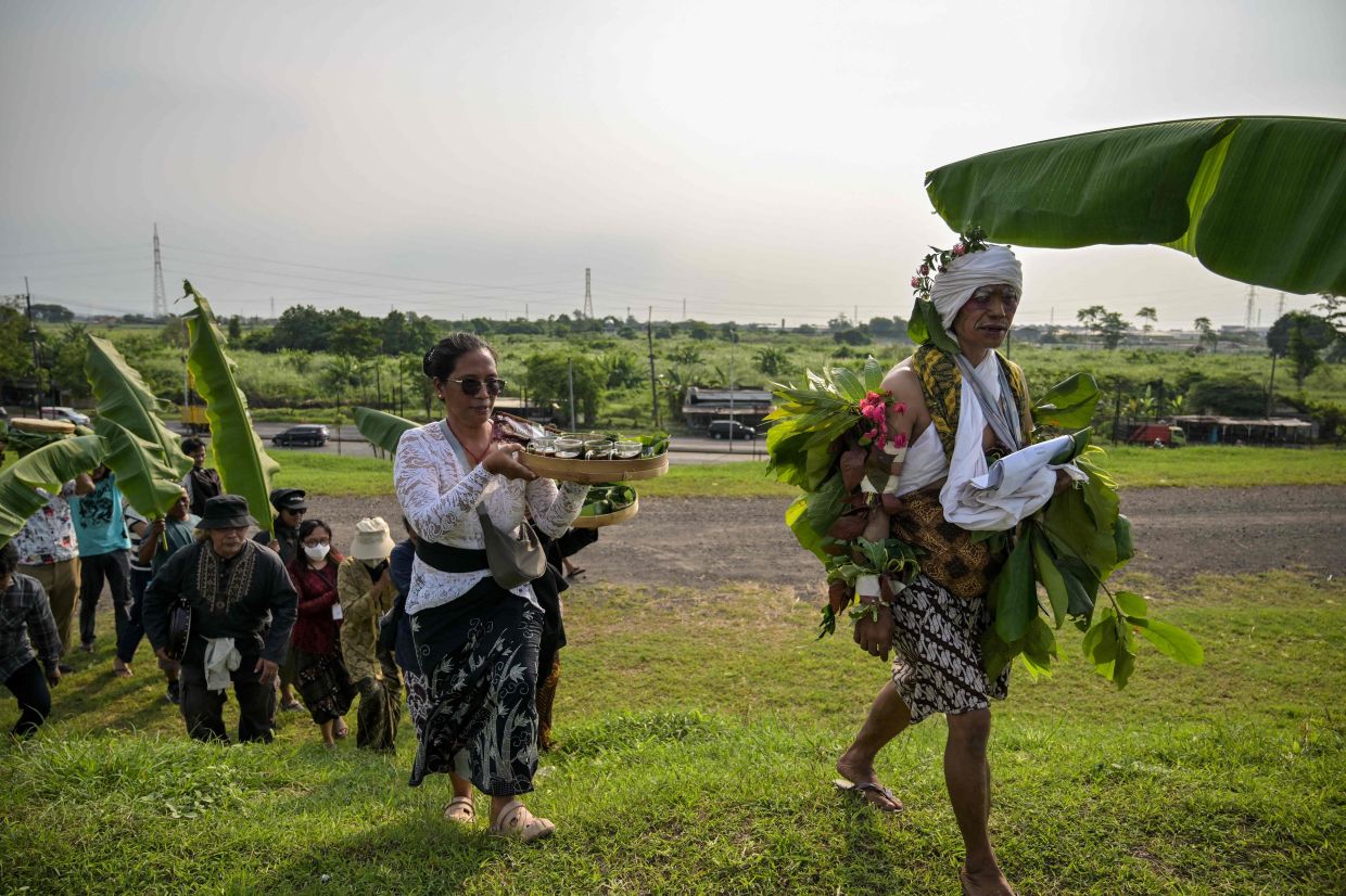 Residents affected by the Lapindo mudflow, together with environmental activists, walk carrying food and offerings towards the embankment in the mud volcano area, marking 20 years since a gas exploration accident triggered a mud flow that inundated more than a dozen villages and permanently displaced tens of thousands of people in Porong, Sidoarjo, East Java province on Friday, May 29, 2026. -- Photo by JUNI KRISWANTO / AFP