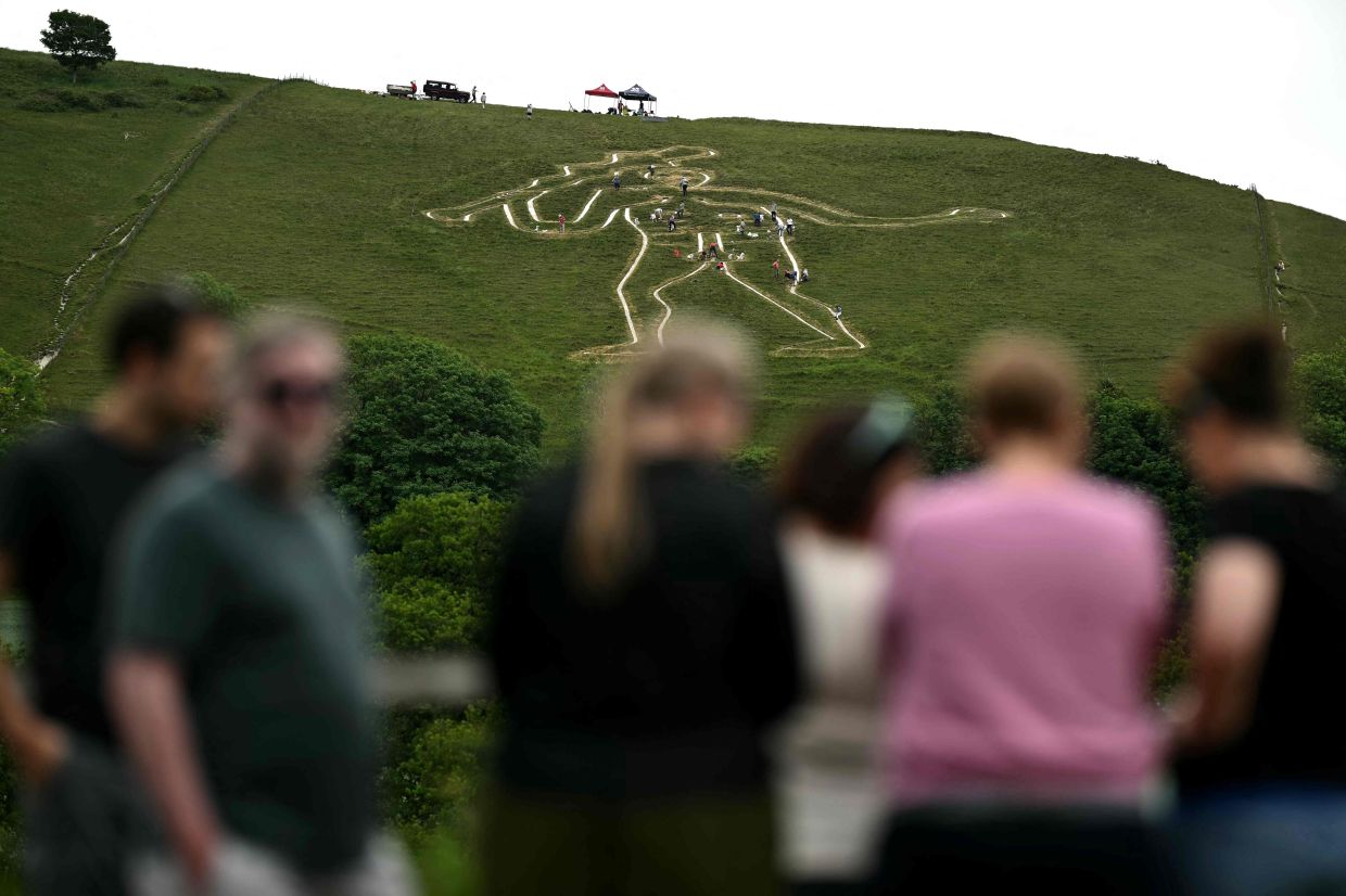 Onlookers watch volunteers at work during the once-a-decade restoration of the Cerne Abbas Giant in Dorchester, southern England. Photo: AFP 