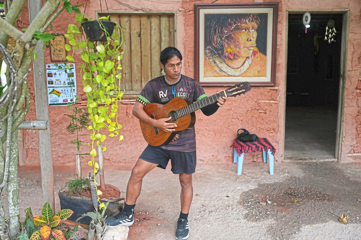 Footballer da Silva plays the guitar at his home in Mata Verde Bonita village.