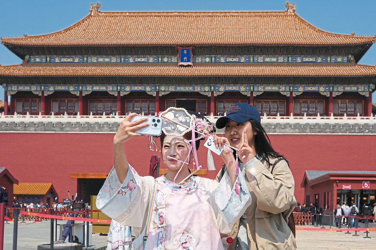 Xiao taking a selfie with a friend while wearing historical Chinese costume outside the Forbidden City in Beijing. — AP 
