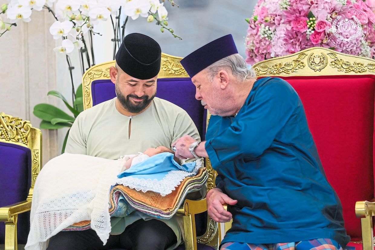 Sultan Ibrahim doting on his newborn granddaughter, Tunku Khadeeja Khayra Iskandariah Tunku Ismail, who is the fifth child of Tunku Ismail (left), during a berandam surai (first hair-cutting) ceremony held at Istana Bukit Serene on May 15.