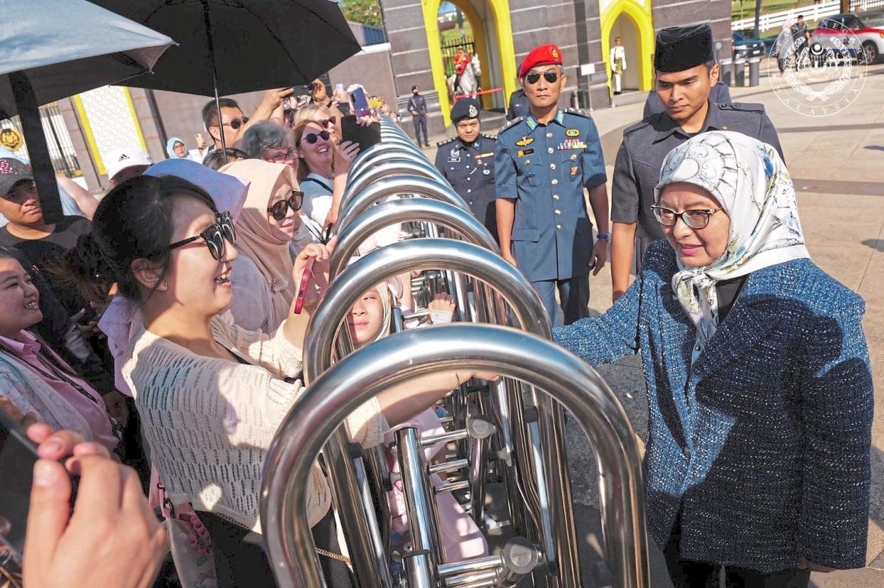 Raja Zarith Sofiah stopping to greet over 100 tourists outside Istana Negara in Kuala Lumpur before continuing her journey back to Johor Baru.