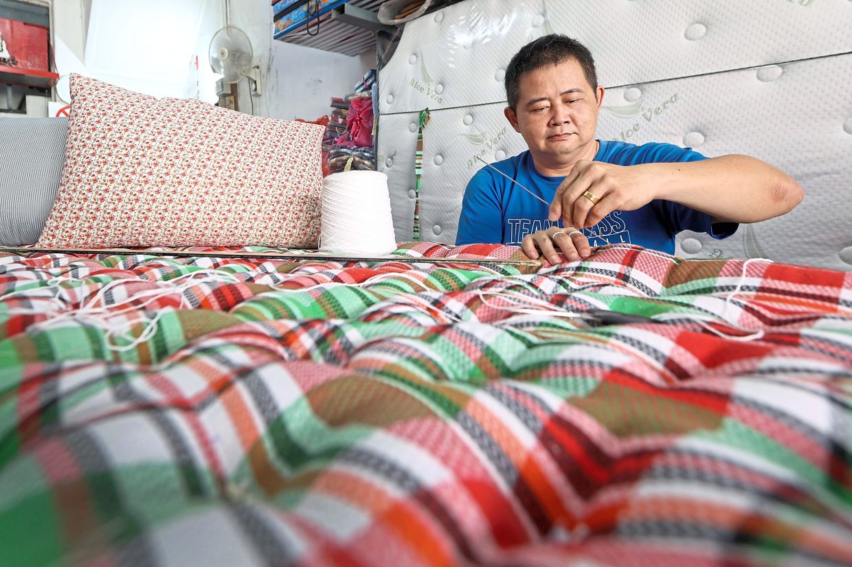 Yeow meticulously hand sewing a traditional mattress filled with kekabu at his shop along Jalan Trus in Johor Baru.The family business has crafted kekabu bedding since the 1960s, counting Sultan Ibrahim as a notable customer.— THOMAS YONG/The Star